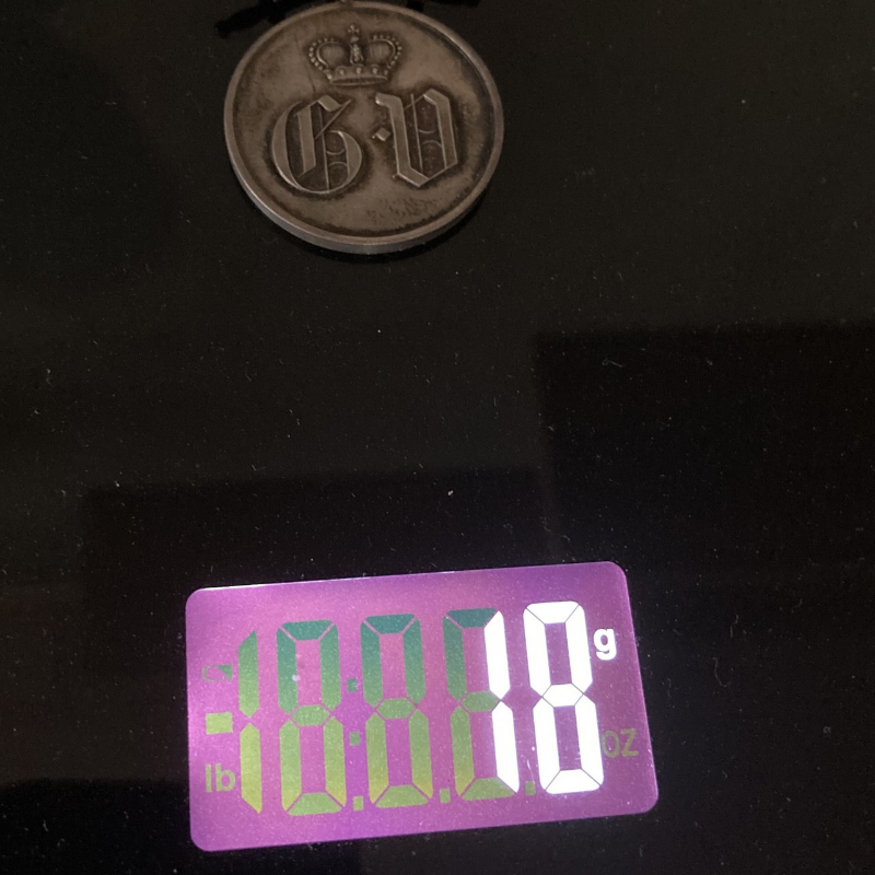 Militaria Medaille auf Waage – Gewichtsanalyse beim Ankauf Alte Militaria-Medaille auf Digitalwaage, Gewichtsanalyse für Wertermittlung und Ankauf von Orden, Abzeichen und Sammlerstücken.