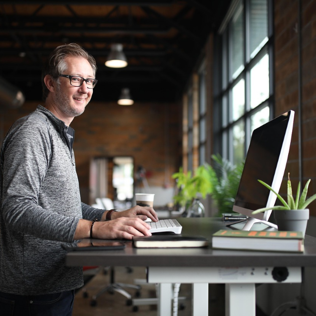 Backoffice – Organisation und Verwaltung Laptop mit Notizbuch und Stift auf Schreibtisch als Symbol für Backoffice-Arbeiten wie Organisation und Verwaltung.