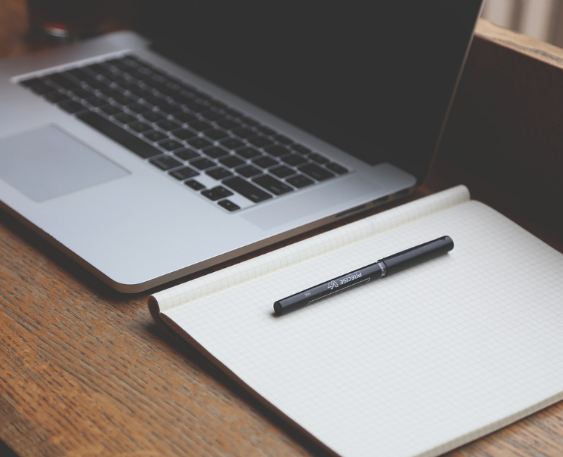 Backoffice – Organisation und Verwaltung Laptop mit Notizbuch und Stift auf Schreibtisch als Symbol für Backoffice-Arbeiten wie Organisation und Verwaltung